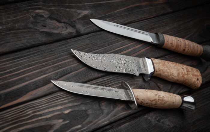 3 knives on a wooden table. Collectible knives, concept image.